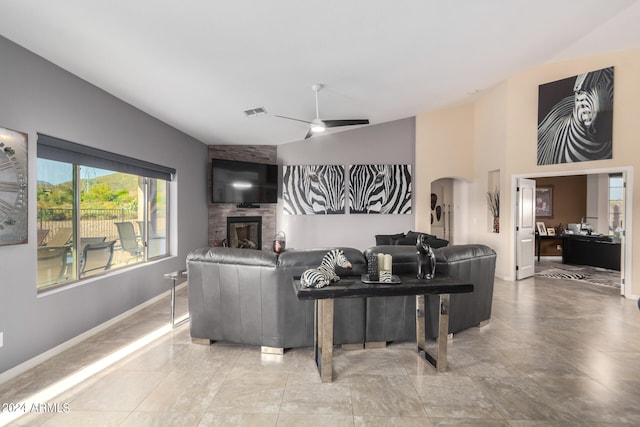 tiled living room featuring lofted ceiling, ceiling fan, and a stone fireplace