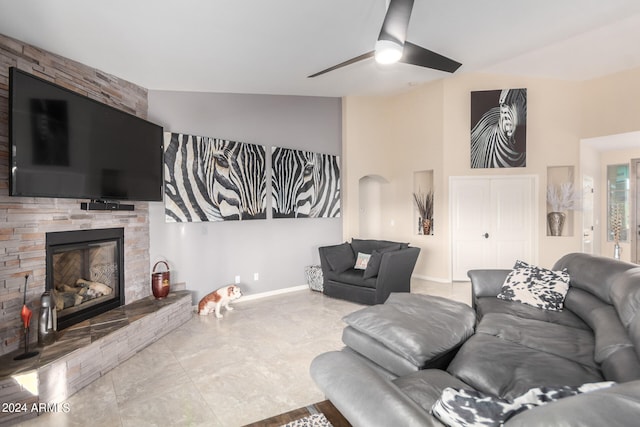 tiled living room with vaulted ceiling, ceiling fan, and a fireplace