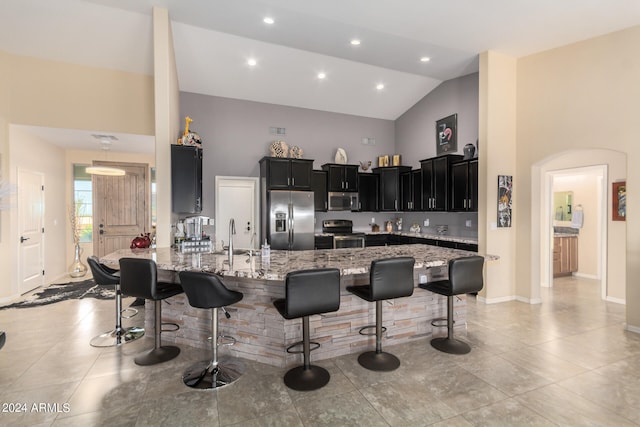 kitchen featuring high vaulted ceiling, stainless steel appliances, a breakfast bar, and light tile floors