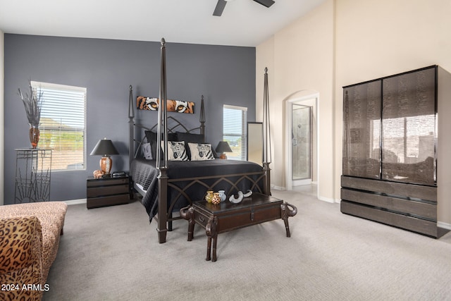 carpeted bedroom with high vaulted ceiling, connected bathroom, and ceiling fan