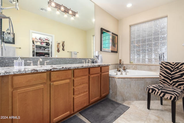 bathroom with double sink, tile floors, oversized vanity, and tiled bath