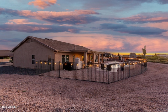 back house at dusk featuring a patio