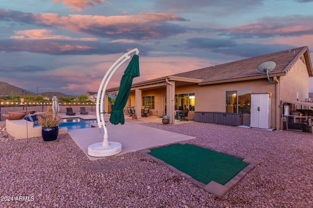 back house at dusk with a patio and a fenced in pool