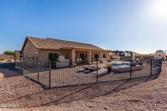 rear view of property featuring a fenced in pool and a patio area