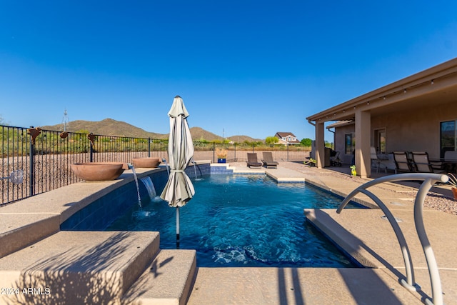 view of pool featuring a mountain view, pool water feature, and a patio area