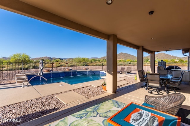 view of swimming pool featuring a mountain view, pool water feature, and a patio