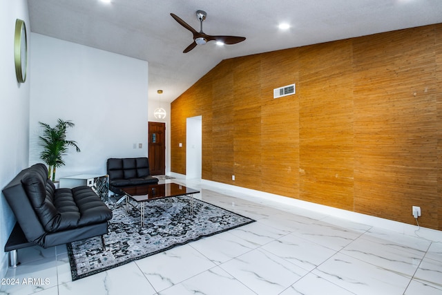 living room featuring lofted ceiling, ceiling fan, and wood walls