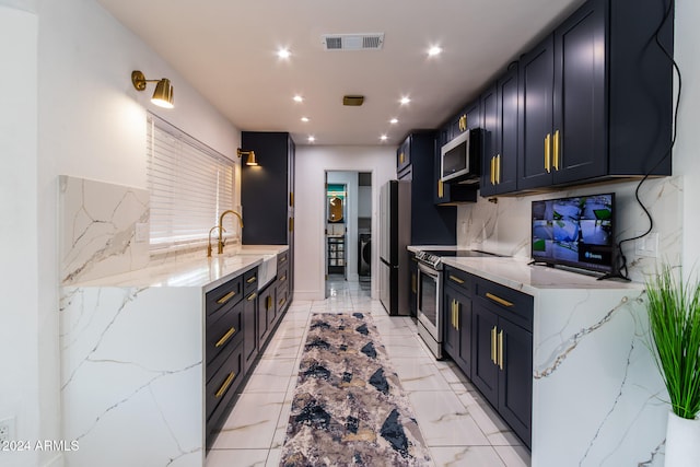 kitchen featuring light stone counters, appliances with stainless steel finishes, sink, and backsplash