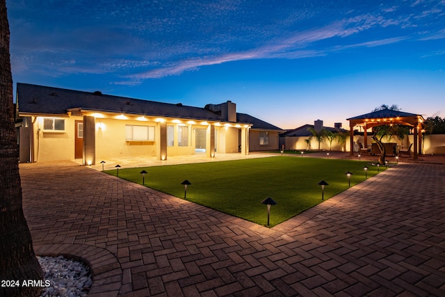 back house at dusk featuring a gazebo, a yard, and a patio