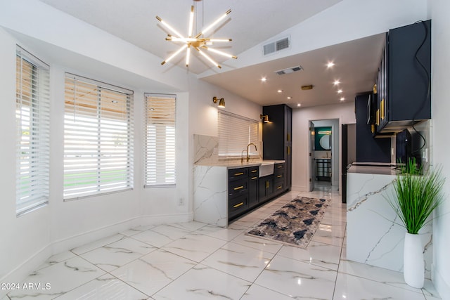 kitchen with a notable chandelier, light stone countertops, sink, and vaulted ceiling