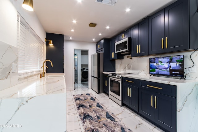 kitchen featuring washer / dryer, light stone counters, stainless steel appliances, and tasteful backsplash