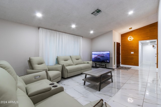 living room with wood walls, a textured ceiling, and vaulted ceiling