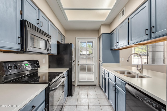 kitchen with light tile patterned floors, a healthy amount of sunlight, sink, and black appliances