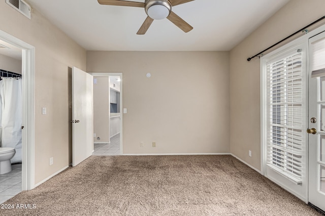 unfurnished bedroom with ceiling fan, light colored carpet, and ensuite bath