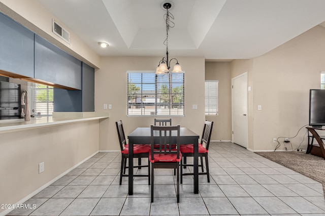 tiled dining area featuring a chandelier and a tray ceiling