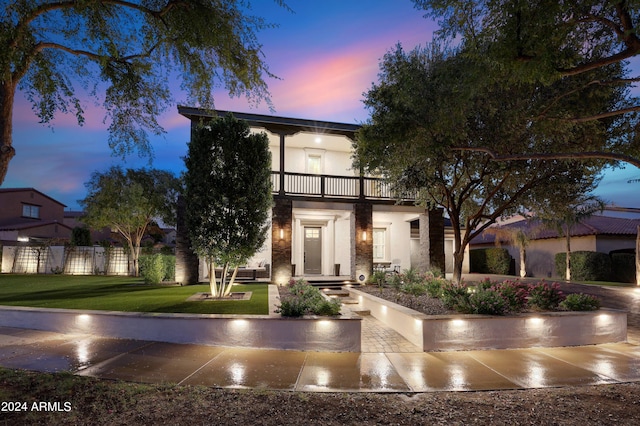 view of front of home featuring a yard and a balcony