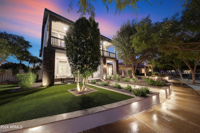 view of front of house with a balcony and a lawn