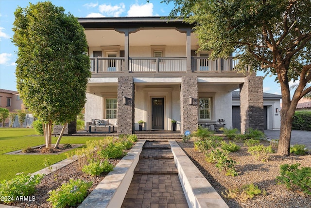 view of front of home with a balcony and a front lawn