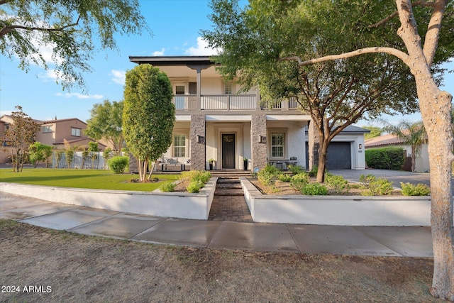 view of front of property featuring a front yard, a balcony, and a garage