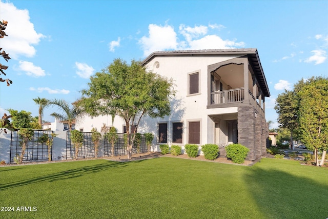 back of property with a yard and a balcony