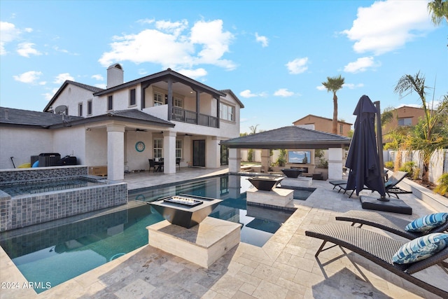 view of pool featuring a gazebo, an in ground hot tub, an outdoor living space with a fire pit, and a patio area