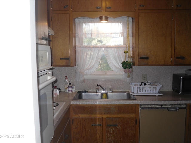 kitchen with tasteful backsplash, dishwashing machine, and sink