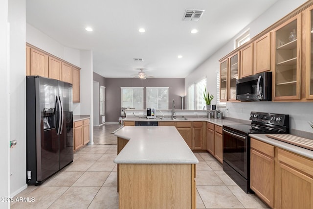 kitchen featuring sink, a center island, light tile patterned floors, kitchen peninsula, and black appliances