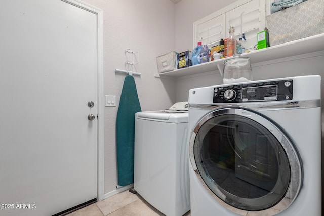 clothes washing area featuring light tile patterned floors and washing machine and clothes dryer