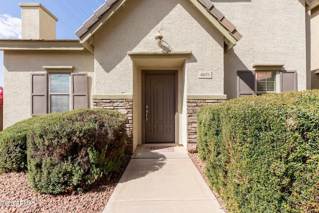 doorway to property with stone siding and stucco siding