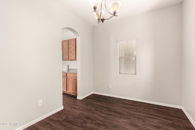 empty room featuring baseboards, dark wood-style flooring, and an inviting chandelier