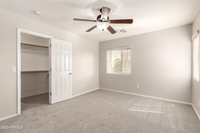 unfurnished bedroom featuring carpet flooring, visible vents, baseboards, a closet, and a walk in closet