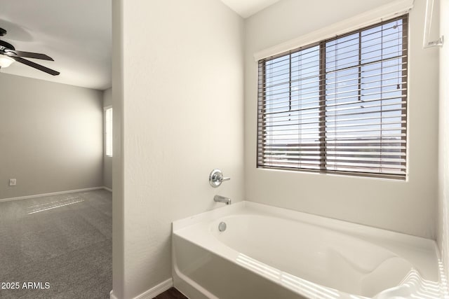 bathroom with a healthy amount of sunlight, a garden tub, and baseboards