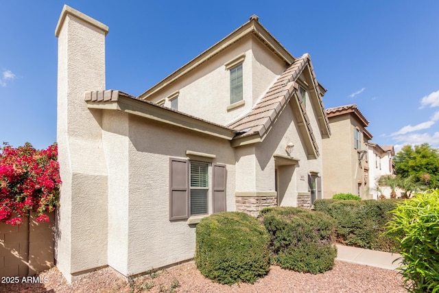 exterior space with stone siding, a tile roof, and stucco siding