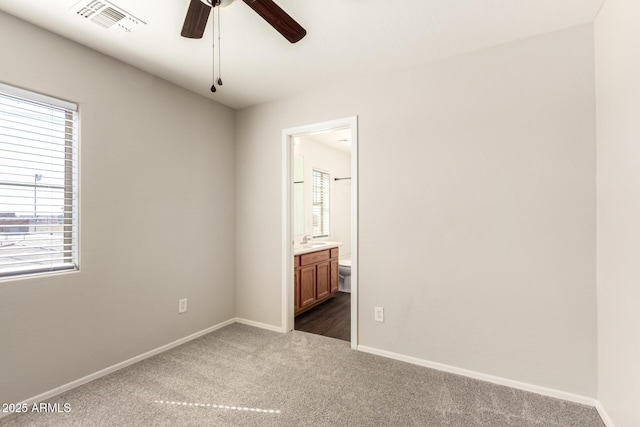 unfurnished bedroom with multiple windows, visible vents, dark colored carpet, and a sink