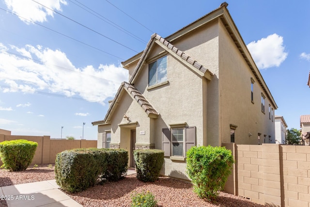 view of front of home featuring a tile roof, fence, and stucco siding