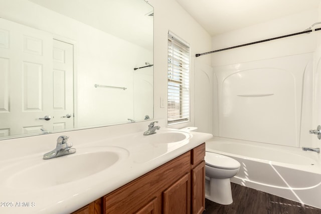 bathroom with toilet, double vanity, tub / shower combination, and a sink