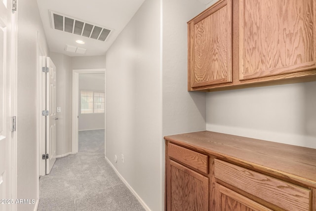 hall featuring light carpet, baseboards, and visible vents