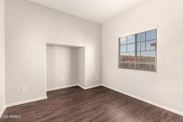 spare room with dark wood-type flooring and baseboards