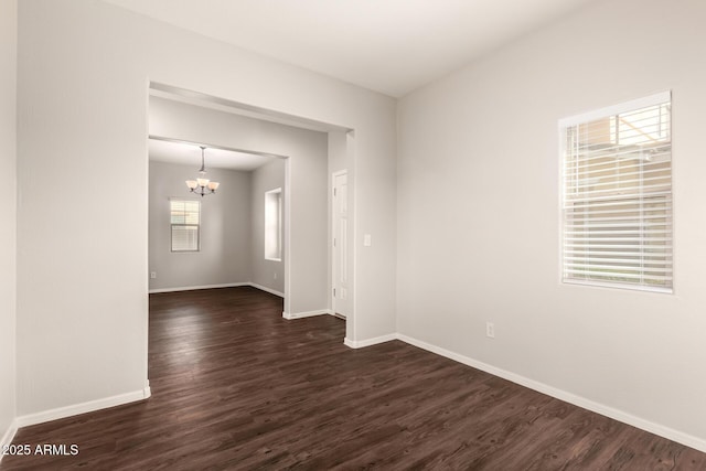 empty room with dark wood-style floors, baseboards, and an inviting chandelier