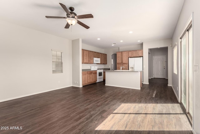 kitchen featuring white appliances, baseboards, dark wood-style floors, brown cabinets, and open floor plan