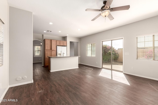 unfurnished living room with recessed lighting, dark wood-style flooring, visible vents, a ceiling fan, and baseboards