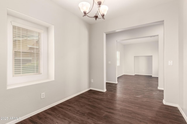 unfurnished dining area featuring a chandelier, dark wood-style flooring, and baseboards