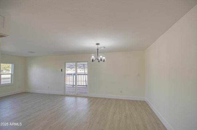 spare room with light hardwood / wood-style floors and an inviting chandelier