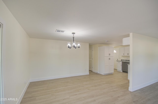 unfurnished room featuring a chandelier and light hardwood / wood-style flooring