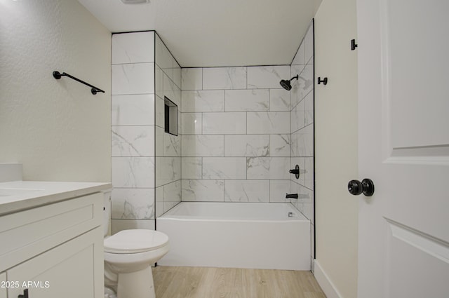 full bathroom featuring wood-type flooring, toilet, tiled shower / bath, and vanity