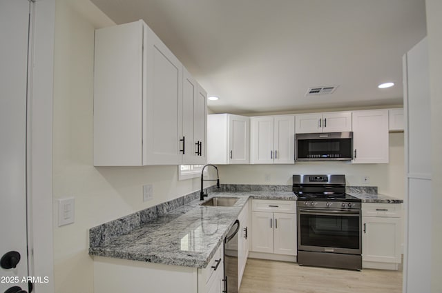 kitchen featuring sink, white cabinets, light wood-type flooring, light stone countertops, and stainless steel appliances