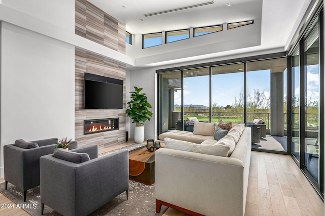 living room with light hardwood / wood-style flooring, a large fireplace, and a towering ceiling