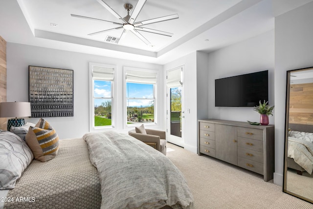 bedroom with light carpet, a tray ceiling, ceiling fan, and access to outside