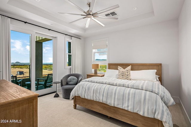 bedroom with ceiling fan, access to exterior, a raised ceiling, and light carpet