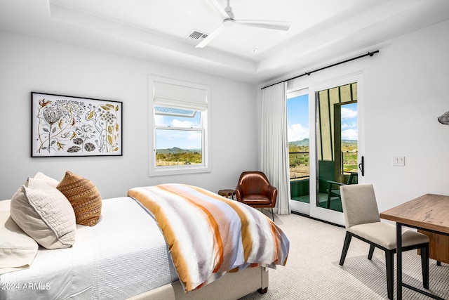 carpeted bedroom with a tray ceiling, ceiling fan, and access to outside